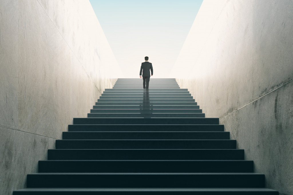 A man in a business suit going up a set of stairs, symbolizing the journey to success