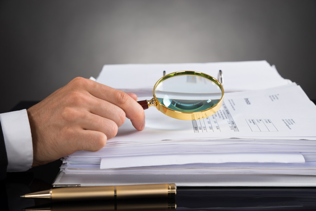 businessman using magnifying glass to analyze financial statements for tax