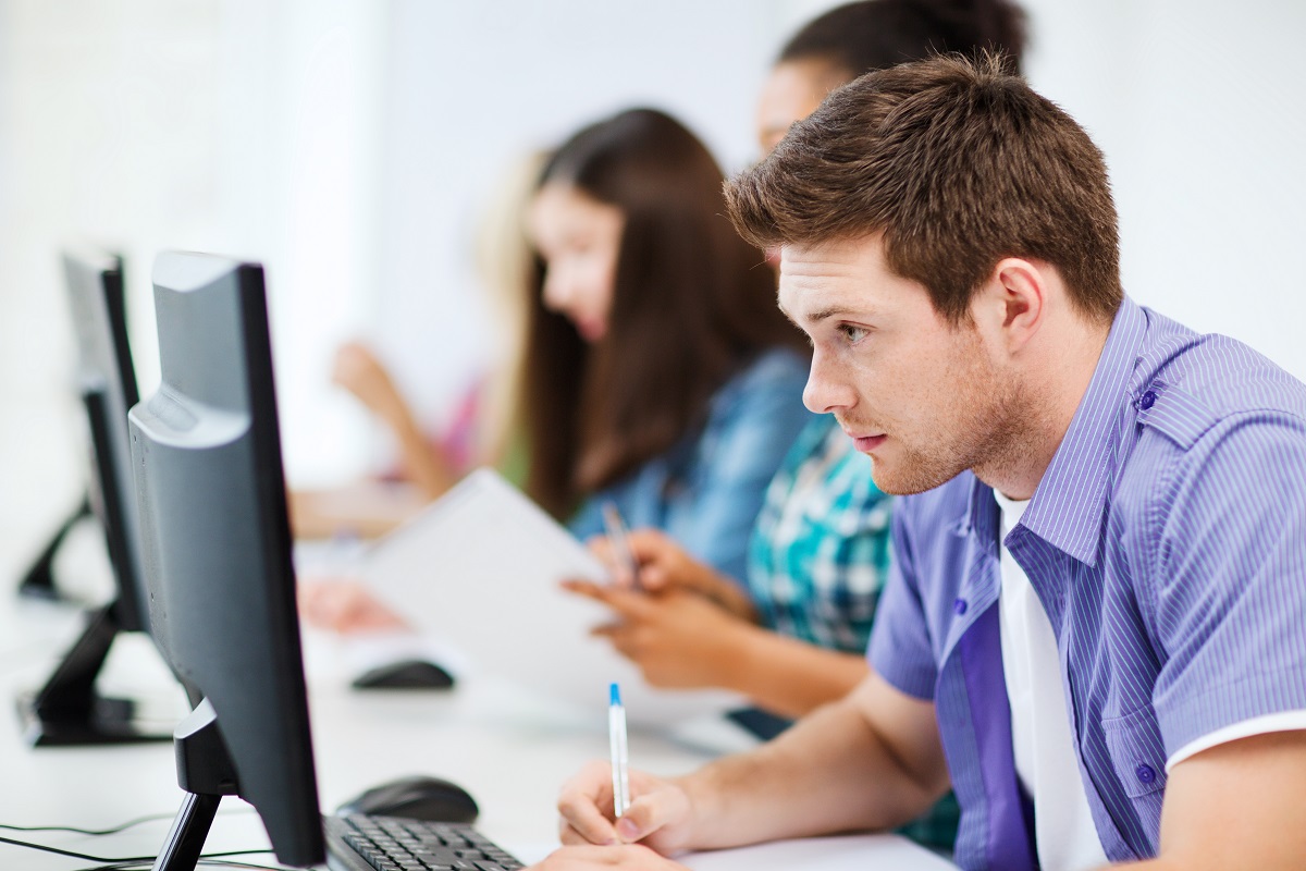 Man writing while looking at the computer